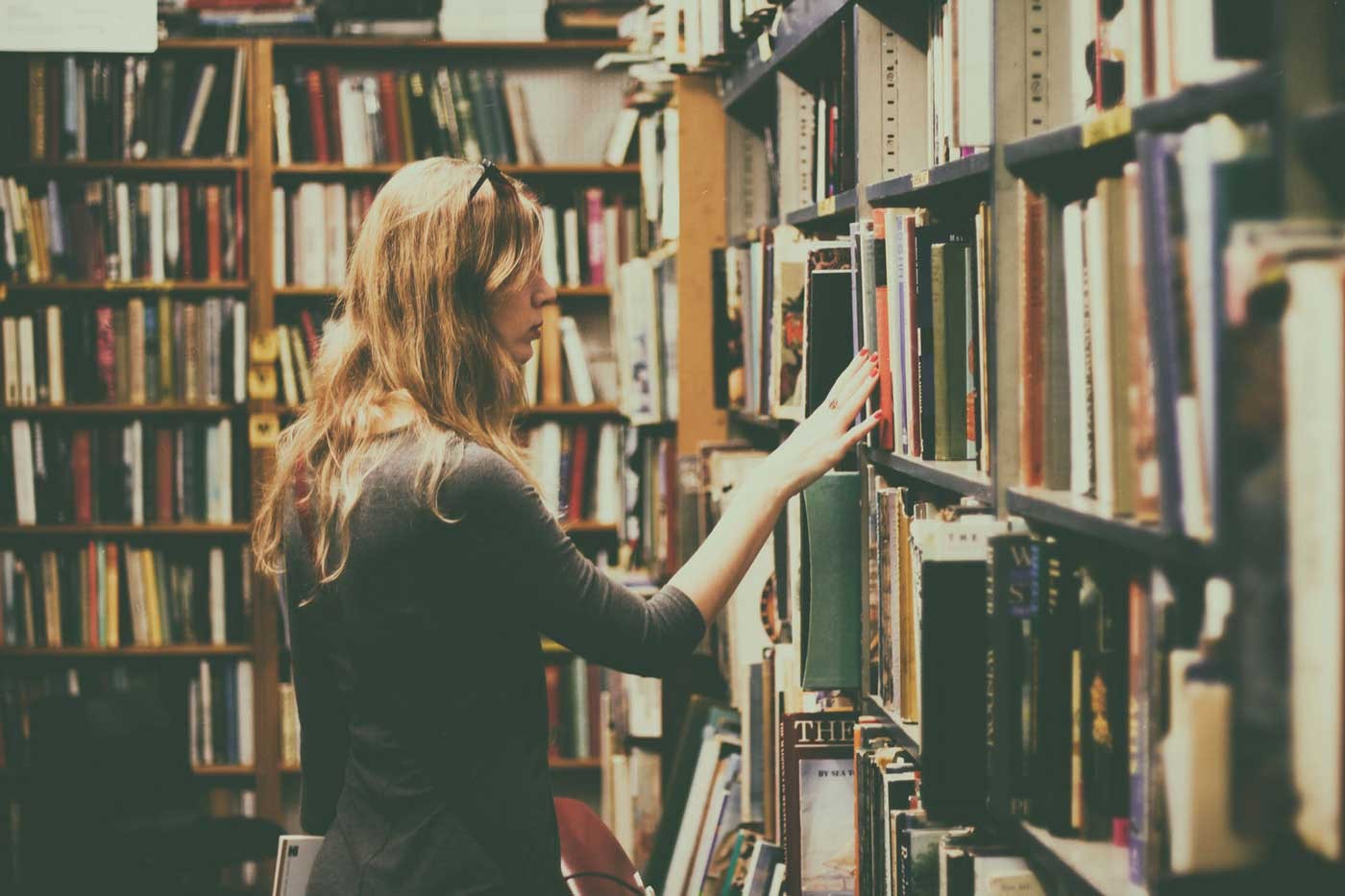 estudiante de nivel de inglés c1 buscando libros en una biblioteca